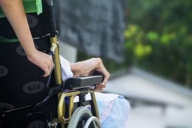 alte Person im Rollstuhl wird von junger Person geschoben